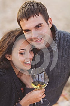 Young happy couple enjoying picnic with white wine on the beach