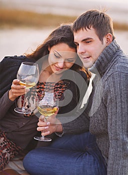 Young happy couple enjoying picnic with white wine on the beach