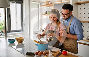 Young happy couple is enjoying and preparing healthy meal in their kitchen together