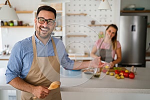 Young happy couple is enjoying and preparing healthy meal in their kitchen together