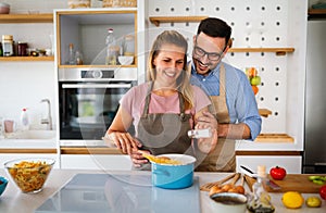 Young happy couple is enjoying and preparing healthy meal in their kitchen together