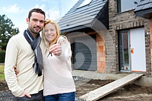 Young happy couple in front of their future house