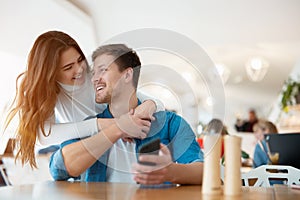 Young happy couple handsome man and beautiful woman hugging her beloved husband on the romantic date at cafe, love and tenderness