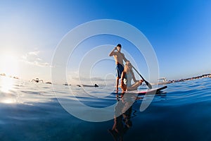 Young happy couple have fun on stand up paddleboard