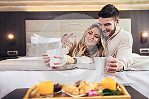 Happy couple having breakfast in luxury hotel room