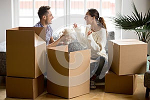 Young happy couple having fun packing boxes in new home