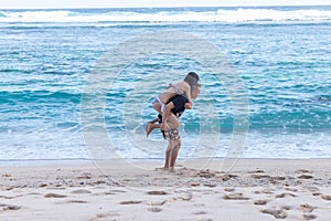Young happy couple having fun on a tropical resort`s white beach of Bali island, Indonesia.