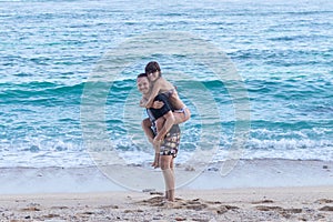 Young happy couple having fun on a tropical resort`s white beach of Bali island, Indonesia.