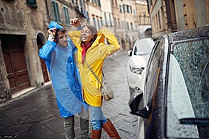 A young happy couple having a good time while walking the city on a rainy day. Walk, rain, city, relationship