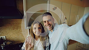 Young happy couple having online video chat in the kitchen at home