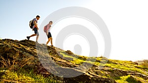 Young Happy Couple Hiking with Backpacks on the Beautiful Rocky Trail at Sunny Evening. Family Travel and Adventure.