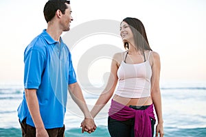 Young happy couple holding hands on beach