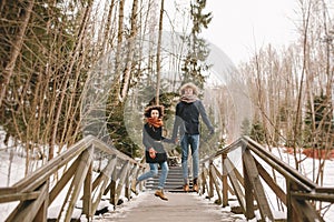 Young happy couple holding hands and jumping in winter park