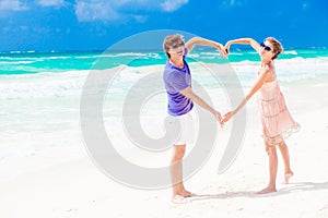 Young happy couple on honeymoon making heart shape