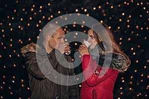 Young happy couple with hot drinks on a winter eve