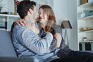 Young happy couple hug on sofa