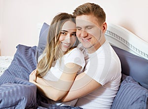 Young happy couple hugging in bed, family in bedroom after sleep, weekend