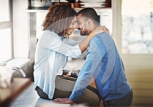 Young happy couple hugging and having a romantic moment in a kitchen at home. Relaxed boyfriend and girlfriend talking