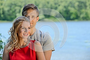 Young happy couple hugging and laughing on river background