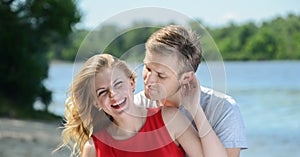 Young happy couple hugging and laughing on river background