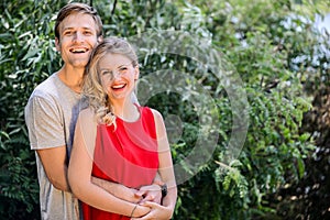 Young happy couple hugging and laughing in the summer park