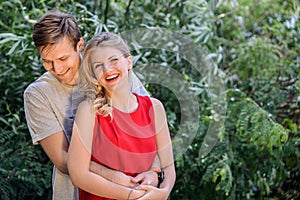 Young happy couple hugging and laughing in the summer park