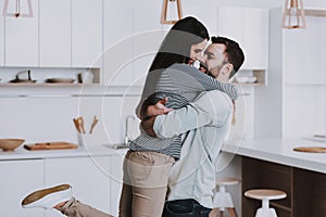 Young Happy Couple Hugging in Modern Kitchen.