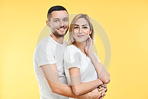 Young happy couple hugging over yellow background