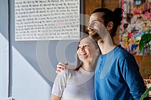 Young happy couple hugging together looking out the window