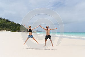 young happy couple jumping on the beach