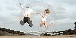 Young happy couple jumping for joy on beach