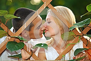 Young happy couple kissing at wooden lattice