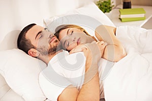 Young Happy Couple Lies in White Bed and Sleep.