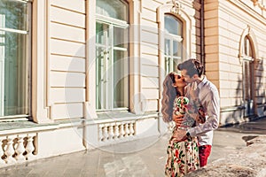 Young happy couple in love hugging and kissing outdoors. Man and woman walking by Pototskykh palace in Lviv