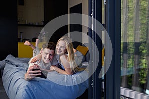 Young happy couple in love lying in bed in morning in their new home in tiny house,and taking selfie, sustainable living