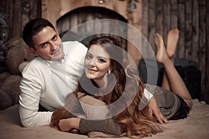 Young happy couple in love lying on rug in cozy wooden interior