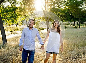 Young happy couple in love together on park landscape sunset with woman pregnant belly