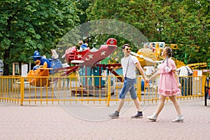 Young happy couple in love walks and has fun in an amusement park