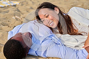 Young happy couple lying on sand, talking enjoying the senses together