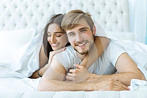 Young happy couple lying together in bed.