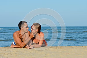 Young happy couple man and woman lying on sandy beach