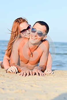 Young happy couple man and woman lying on sandy beach