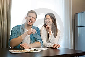 Young happy couple man and woman sitting in their new cosy appartments after successful lease sign both smiling