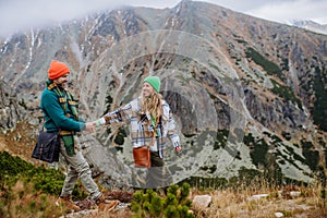 Young happy couple at mountain hike, holding hands.