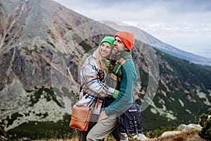 Young happy couple at mountain hike, hugging each other.