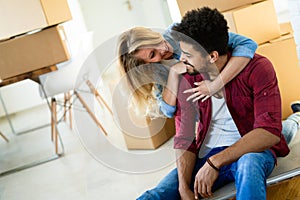 Young happy couple moving in new home and unpacking boxes