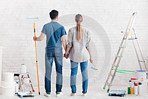 Young happy couple planning to paint their new home interior