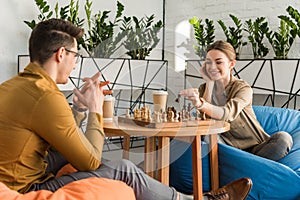 young happy couple playing chess while sitting photo
