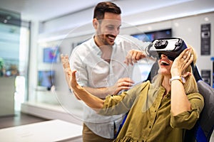 Young happy couple playing video games with virtual reality glasses in technical store