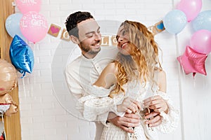 Young happy couple posing with baby shoes during gender reveal party photo